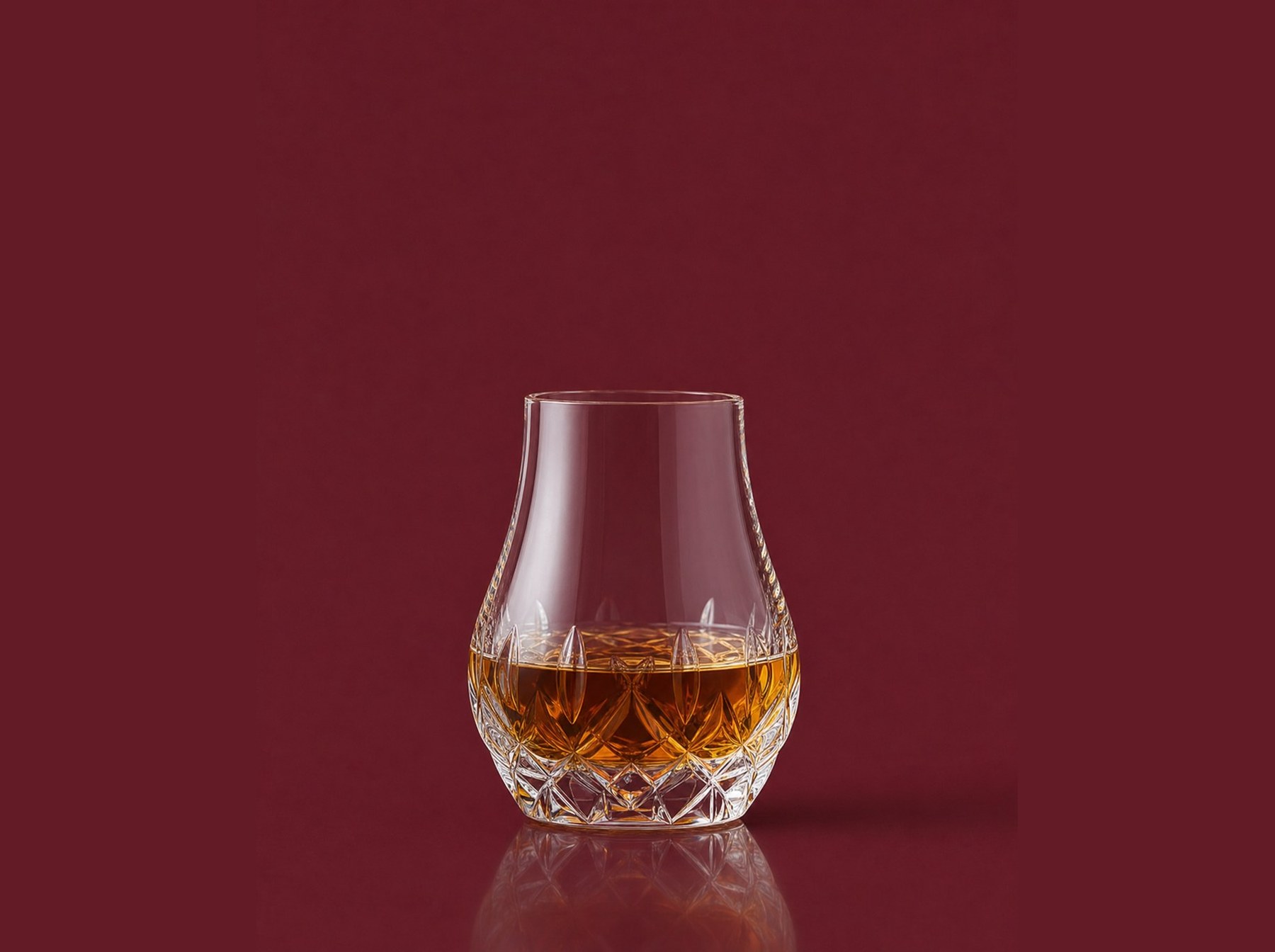 A glass of amber single-malt whisky on a deep wine-red background